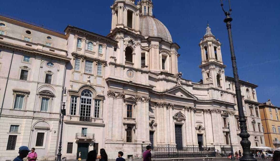 Maestosa chiesa barocca nel cuore di Roma con dettagli architettonici intricati e una grande cupola, visitata da turisti e appassionati di arte religiosa.