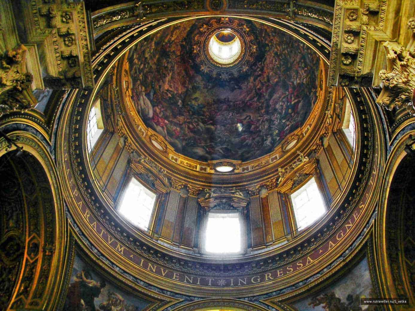 Sant'Agnese in Agone a Roma: luoghi da vedere in stile barocco 4 Lusso e arte barocca in una chiesa storica con soffitto affrescato e decorazioni dorate. La cupola mostra dettagli artistici e luminose finestre che illuminano l'interno.