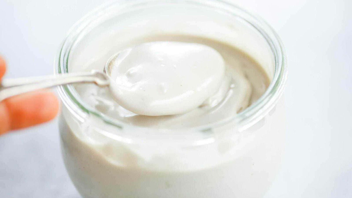 Crema di yogurt bianco in barattolo con cucchiaio, alimento salutare e gustoso, ideale per colazioni e snack nutrienti, perfetta per ricette di dolci e dessert salutari.