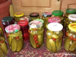 Cattive pere e pomodorini sott'olio in barattoli di vetro, conservate per l'inverno, su una tovaglia rossa e sfondo in legno.
