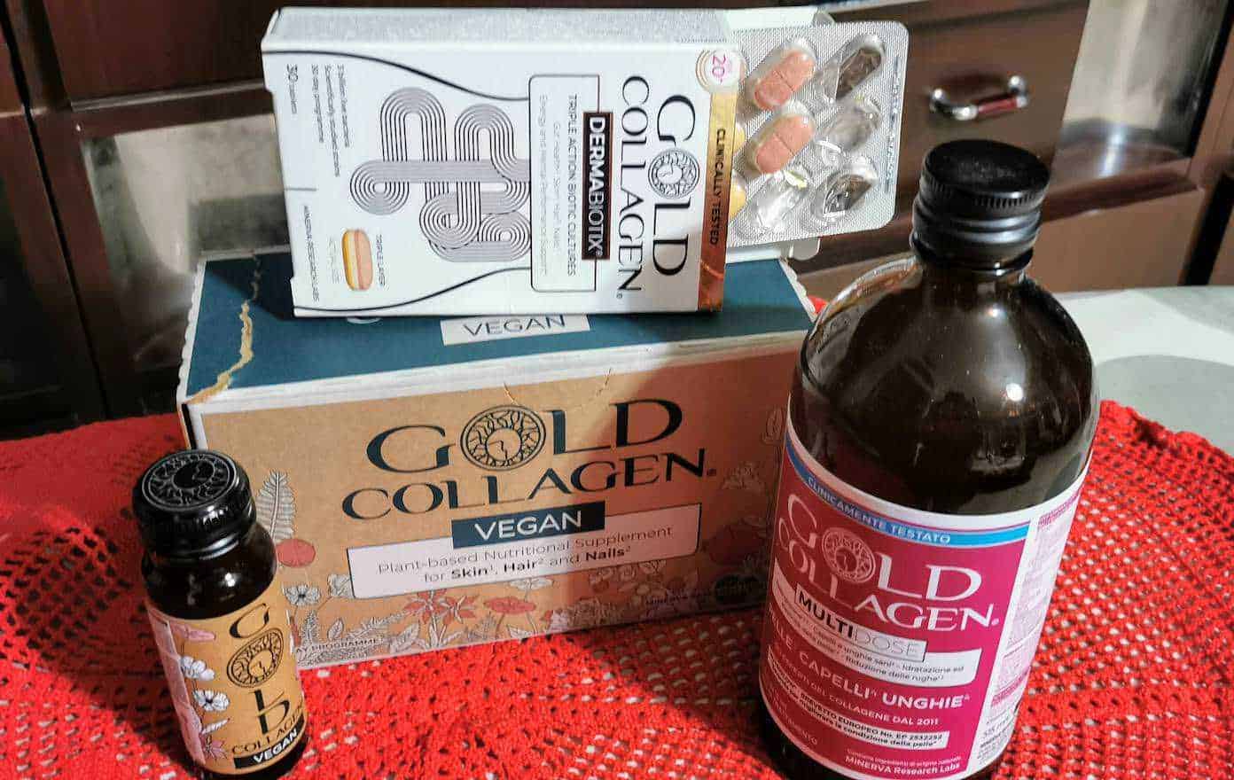 Integratore di collagene vegano Gold Collagen e integratore multivitaminico in bottiglia e scatola, prodotti naturali per pelle, capelli e unghie su tovagliolo rosso, sito Appunti Sul Blog.