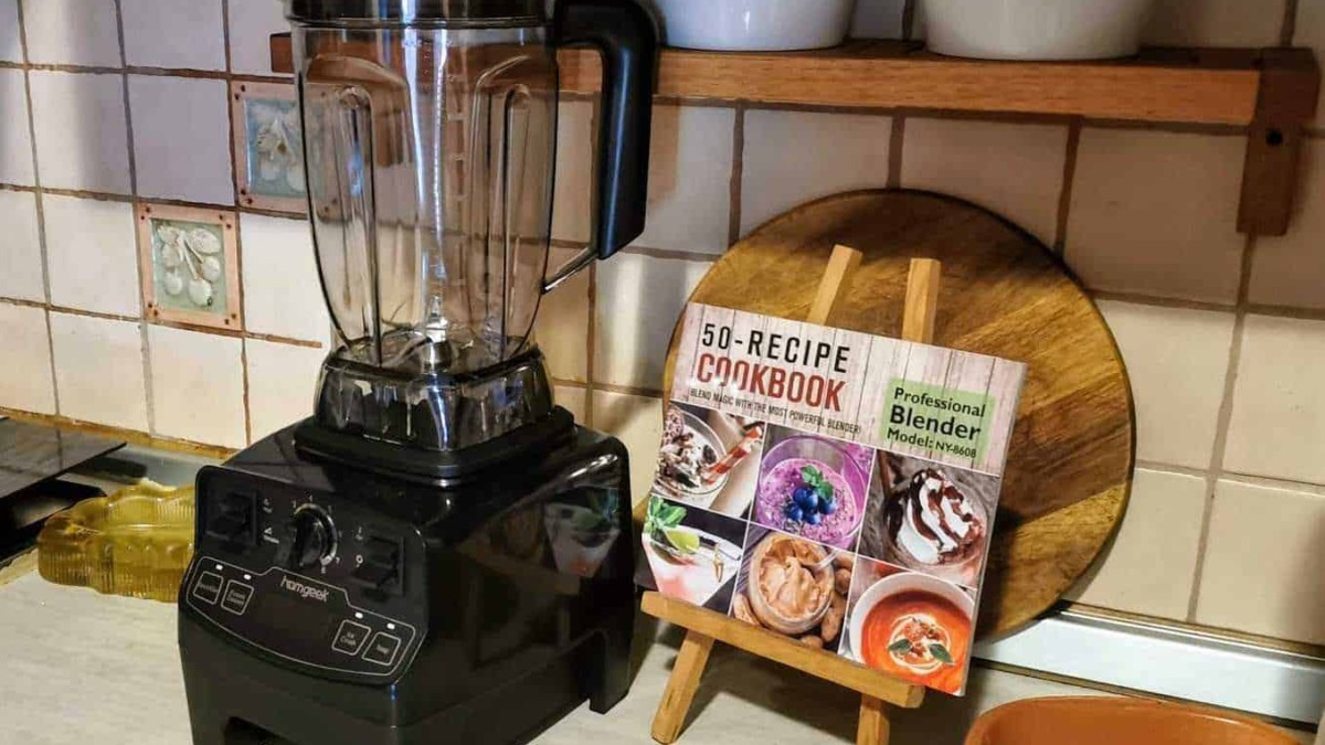 Vitamina, frullatore e ricettario su cucina casalinga per preparare smoothie e smoothie bowl sani e gustosi. Accessorio essenziale per chi ama frullare frutta e verdura per uno stile di vita salutare.