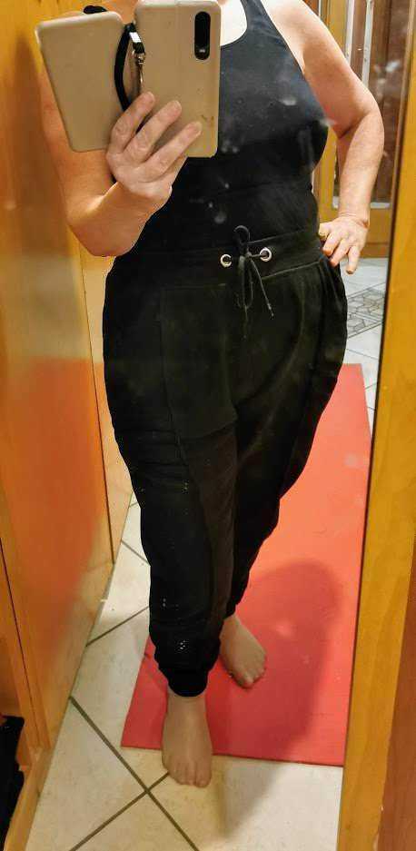 Completo nero con pantaloni jogger e top senza maniche, specchio per selfie, abbigliamento casual e confortevole.