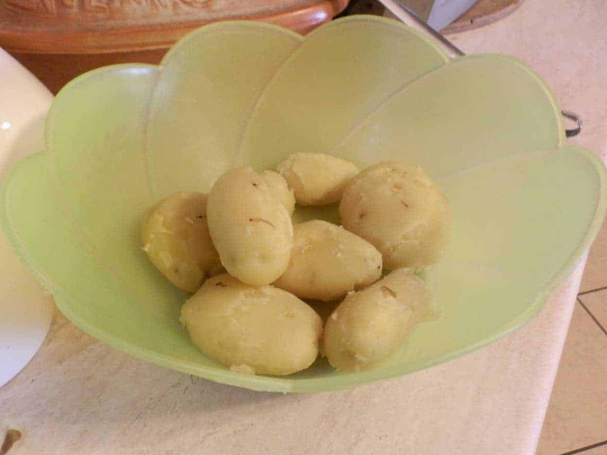 Pomodorini di patate novelle in ciotola verde, pronti per essere cotti o utilizzati in ricette rustiche e genuine, ideale per piatti tradizionali italiani.