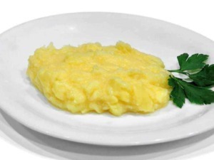 Pulitura delle patate lessate con prezzemolo su piatto bianco, ricetta semplice italiana.