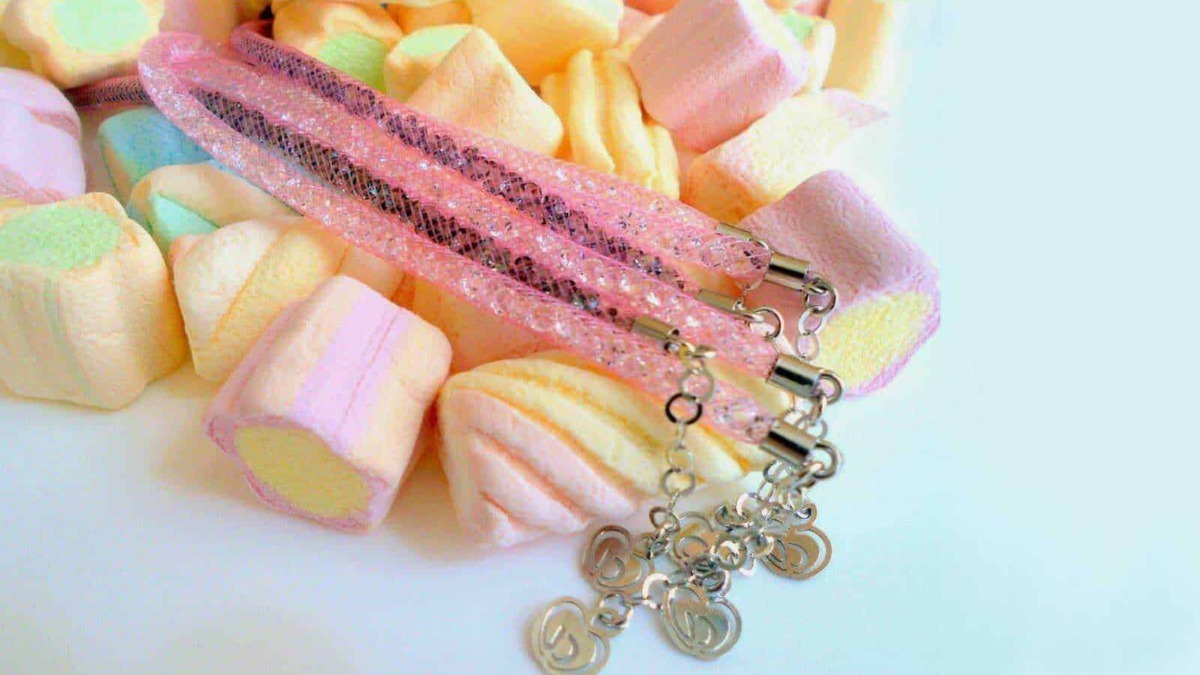 Collana con pendente a cuore in metallo, decorata con dettagli glitterati, posata su marshmallow colorati di zucchero, dolci e allegri, perfetta come accessorio moda o regalo romantico.
