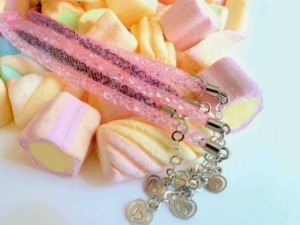Collana con pendente a cuore in metallo, decorata con dettagli glitterati, posata su marshmallow colorati di zucchero, dolci e allegri, perfetta come accessorio moda o regalo romantico.