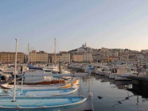 Barche da diporto ormeggiate nel porto di Nizza, veduta dai pontili con sfondo la città e il Castello di Nizza al tramonto, immagine di alta qualità per turismo e nautica.