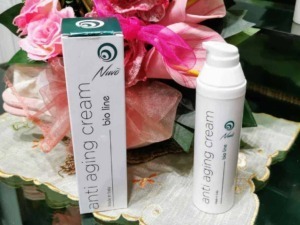 Crema antirughe bio line su tavolo con fiori rosa, prodotto per la cura della pelle e antietà naturale, packaging elegante e semplice per un beauty naturale e biologico.