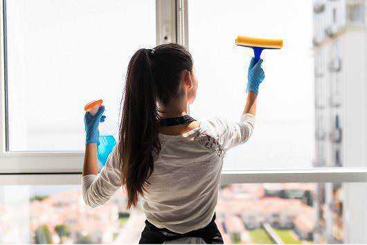Ammoniaca in casa: Pulizia finestra con detergente e spatola, donna che si prende cura della casa.