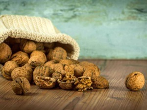 Noce in guscio e sgusciate su tavola di legno con sfondo verde vintage.