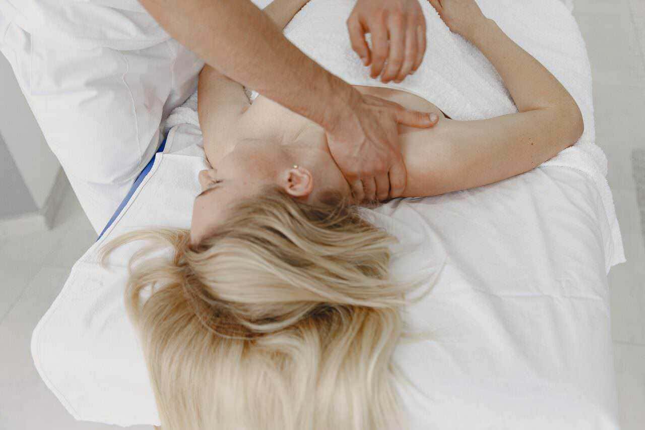 8 benefici cura chiropratica. Cosa cura la chiropratica 3 Massaggiatore che compie un massaggio rilassante su una donna sdraiata su un lettino da massaggi, approccio terapeutico e benessere, trattamento decontratturante e relax muscolare.