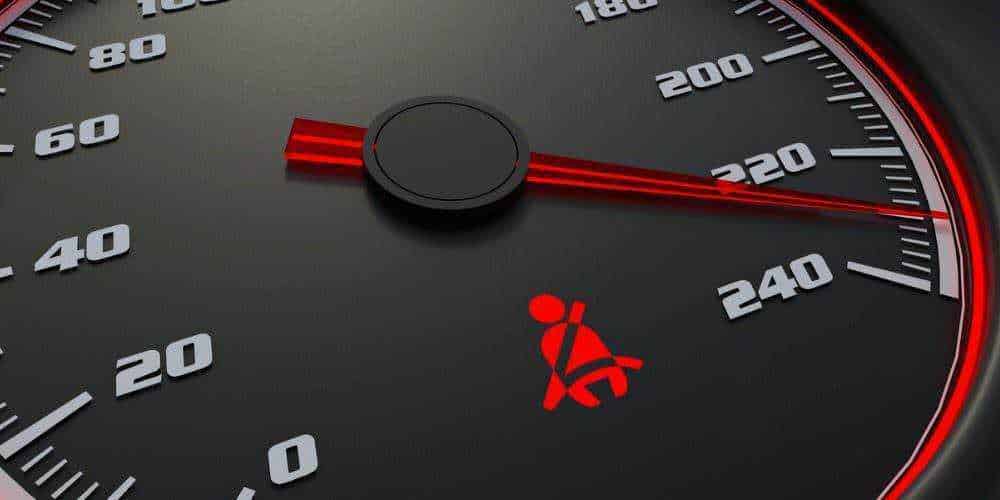 Cosa significano le spie sul cruscotto, 10 icone auto luminose 12 Tachimetro auto con indicatore di velocità, simbolo di cintura di sicurezza accanto, dettaglio di sicurezza e velocità del veicolo.