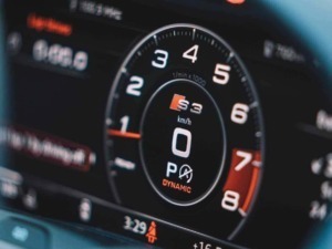 Veloce volante di un'auto sportiva con display digitale, mostra velocità in km/h, motore turbo, e indicatori di modalità di guida per appassionati di auto e motori.