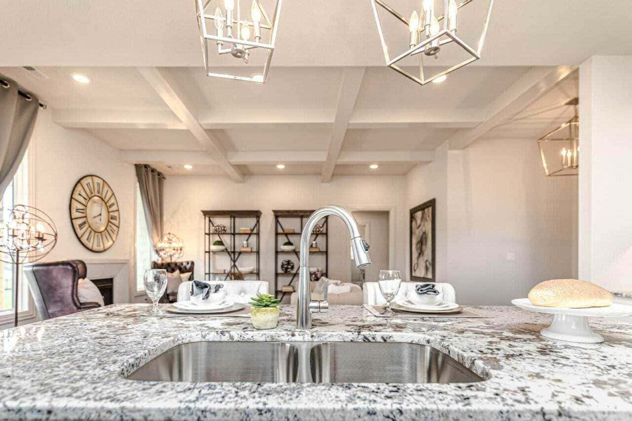 Lavandino in cucina con piano in granito, elegante illuminazione moderna, soggiorno luminoso e arredato, decorazione minimalista, esempio di design e stile di vita raffinato.