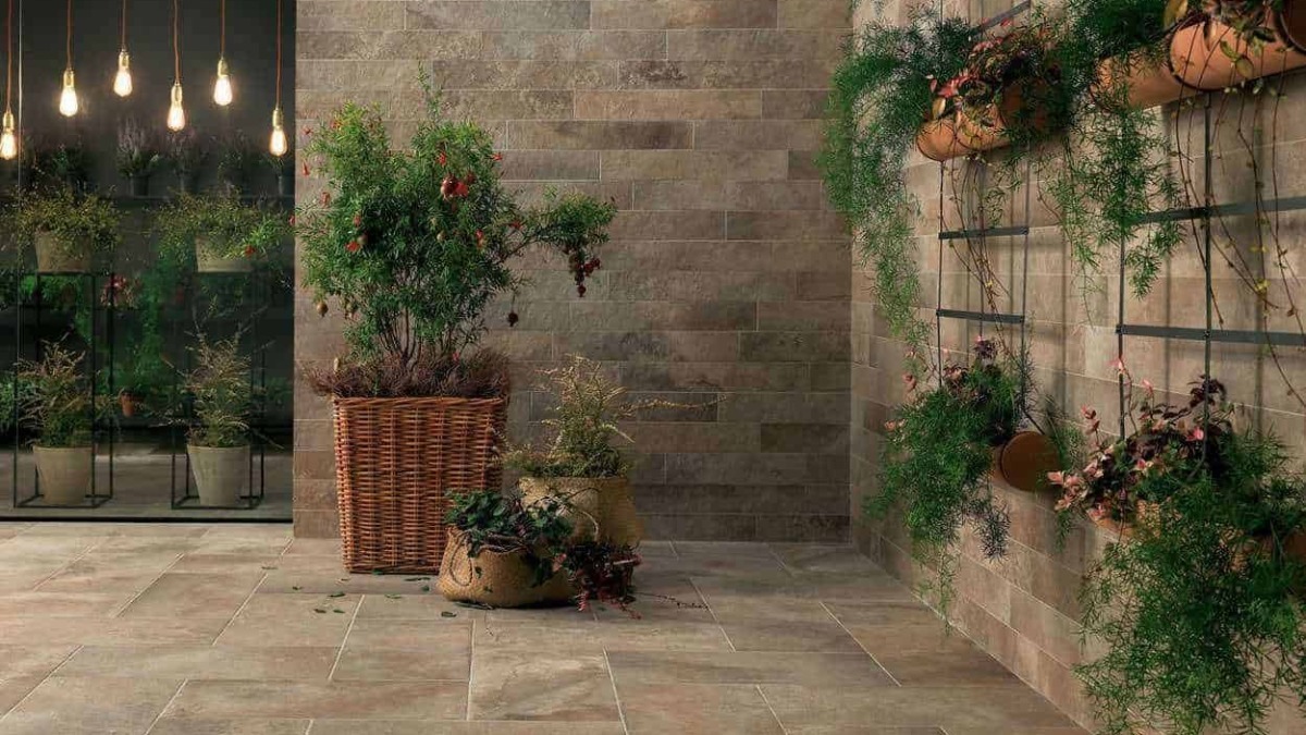 Fogli di piante verdi e fiori in fioriere di terracotta e insets di metallo su pareti di mattoni in stile moderno, ambiente lussuoso e accogliente, decorazione di interni elegante e naturale.