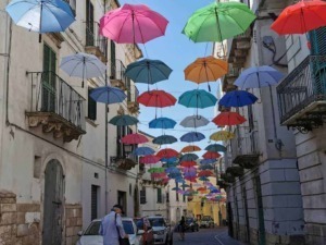 Colorati ombrelli appesi sopra strade di un quartiere storico, decorazione artistica e colorata creata per abbellire l'ambiente e attirare visitatori, perfetta per foto e giornate di sole.