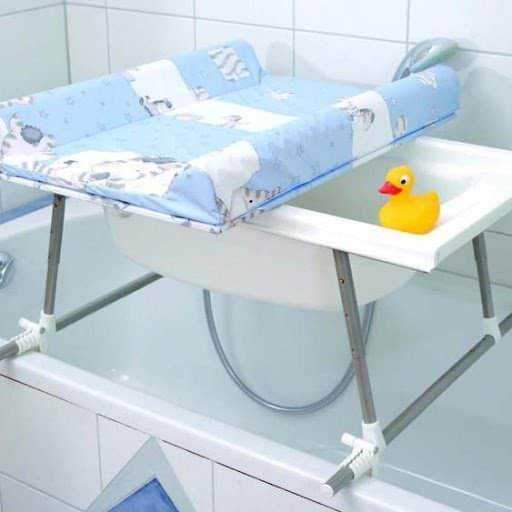 Culla per neonati con copertina azzurra e papera galleggiante gialla sul fasciatoio in bagno, ambiente pulito e sicuro per il cambio del neonato.