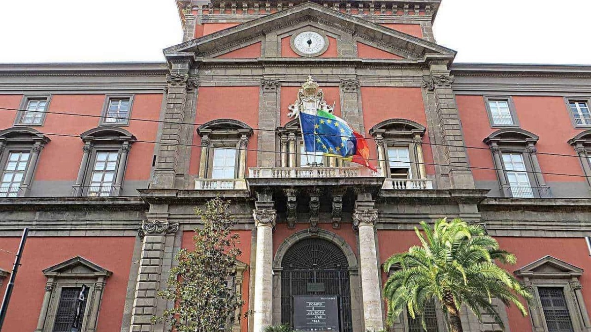 Palazzo storico con flags italiani ed europee, architettura classica, strada animata con persone, piante tropicali, atmosfera cittadina, centro città, edificio istituzionale, turismo a Palermo.