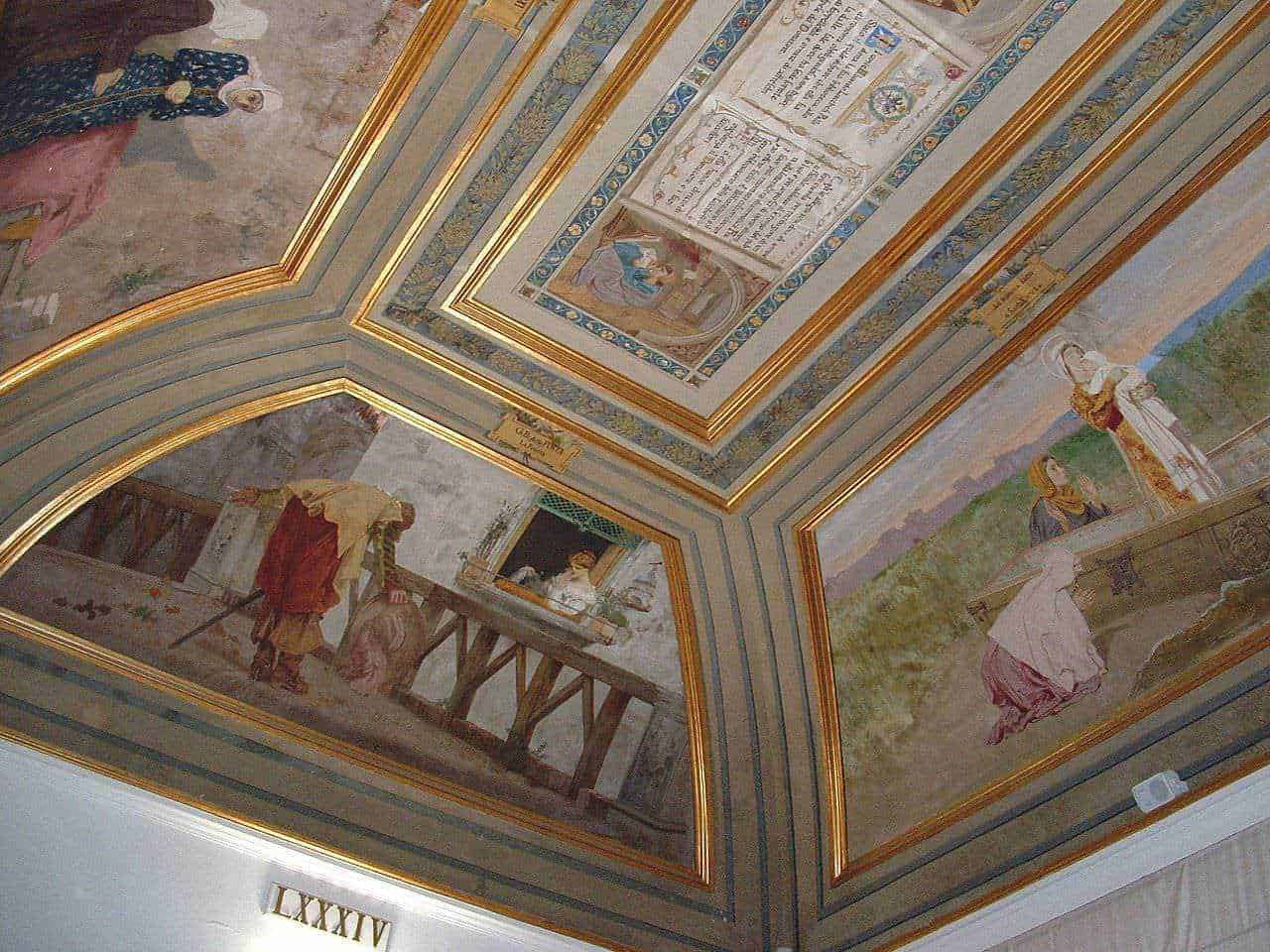 Fresque murale decorativa con scene storiche e dettagli dorati, dipinta sul soffitto di un edificio antico, rappresenta figure che interagiscono in ambientazioni tradizionali italiane.
