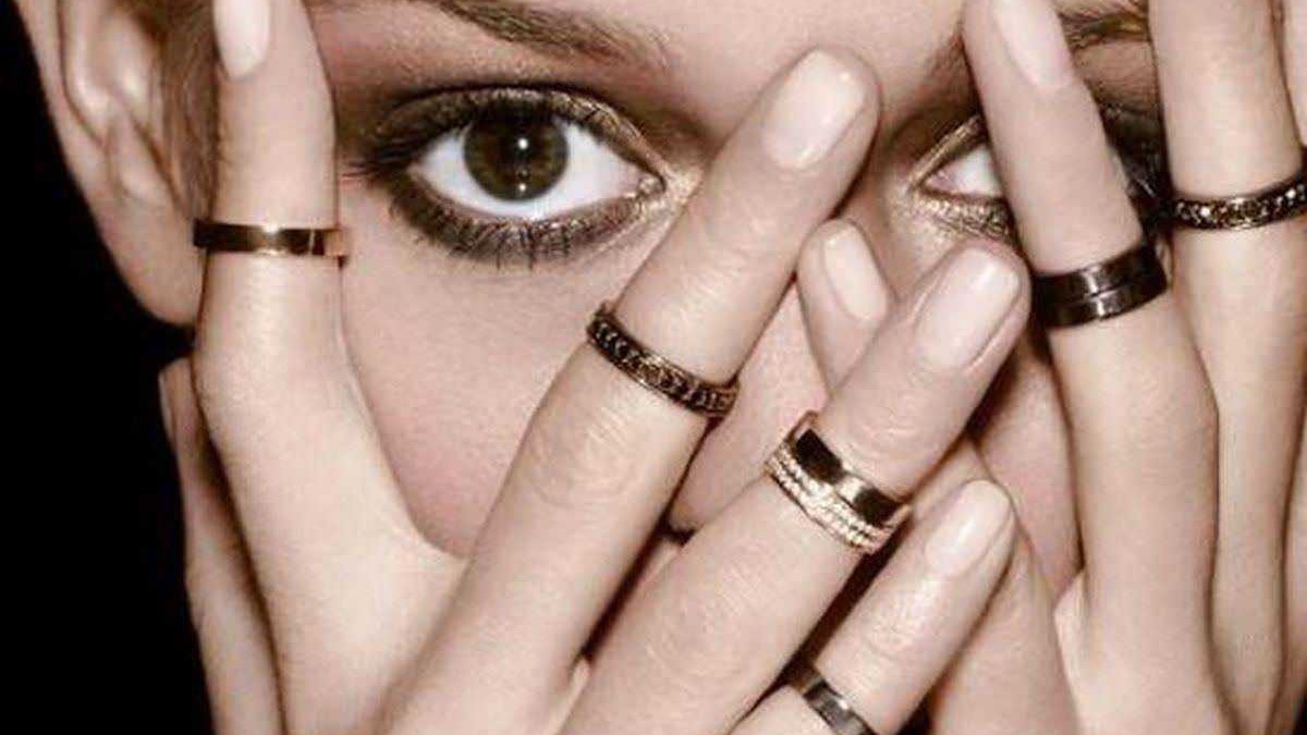 Occhio di donna con anelli sulle dita, focus su espressione intensa, moda e accessori di tendenza, angolo ravvicinato, stile glamour, immagini di moda.