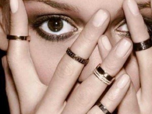 Occhio di donna con anelli sulle dita, focus su espressione intensa, moda e accessori di tendenza, angolo ravvicinato, stile glamour, immagini di moda.