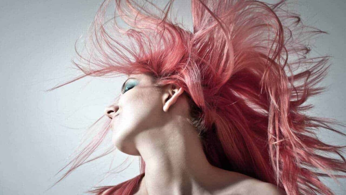 Capelli acconciatura rivoluzionaria colore rosa, immagine di una donna con capelli lunghi e mossi in movimento, stile moderno e creativo, perfetta per tema di moda, bellezza e tendenze.