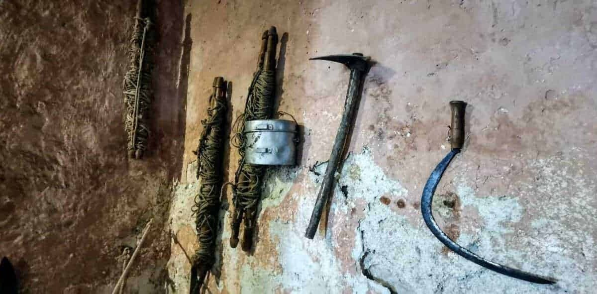 Vecchi attrezzi da lavoro appoggiati su parete rustica, strumenti di uso manuale e invecchiato, adatti a lavori di muratura o edilizia.