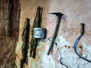 Vecchi attrezzi da lavoro appoggiati su parete rustica, strumenti di uso manuale e invecchiato, adatti a lavori di muratura o edilizia.