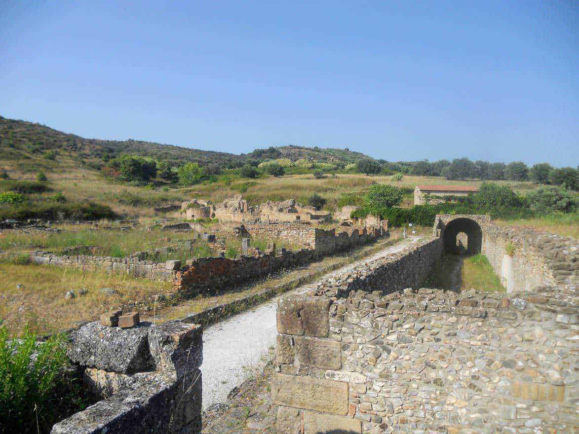 Costiera cilentana posti da visitare tra mare e terra 3 Antico sito archeologico di Roma antica con resti di mura e porte, immerso in un paesaggio collinare verde, ideale per appunti su storia e archeologia.