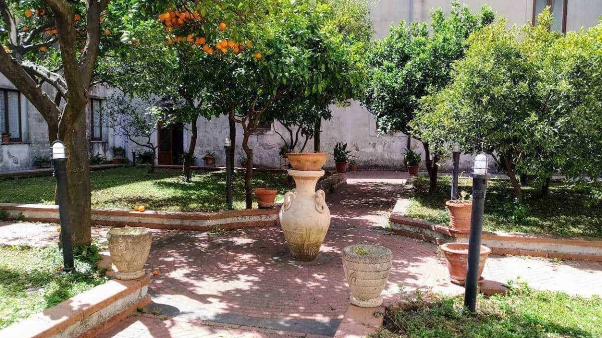 Elegante giardino con alberi da frutto, vasi decorativi e illuminazione esterna, ideale per relax e convivialità all'aperto. spazio verde curato e accogliente con piante e fiori.
