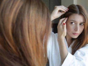 Capelli rossi, donna che si sistema i capelli di fronte allo specchio, cura della bellezza, hair care, routine di bellezza, look personalizzato, autostima, stile e immagine.