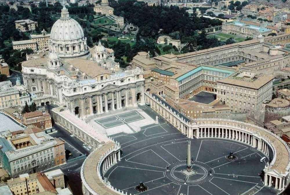 Immagine aerea di San Pietro e Piazza San Pietro a Roma, con la basilica e le statue storiche, vista dall'alto durante il giorno.