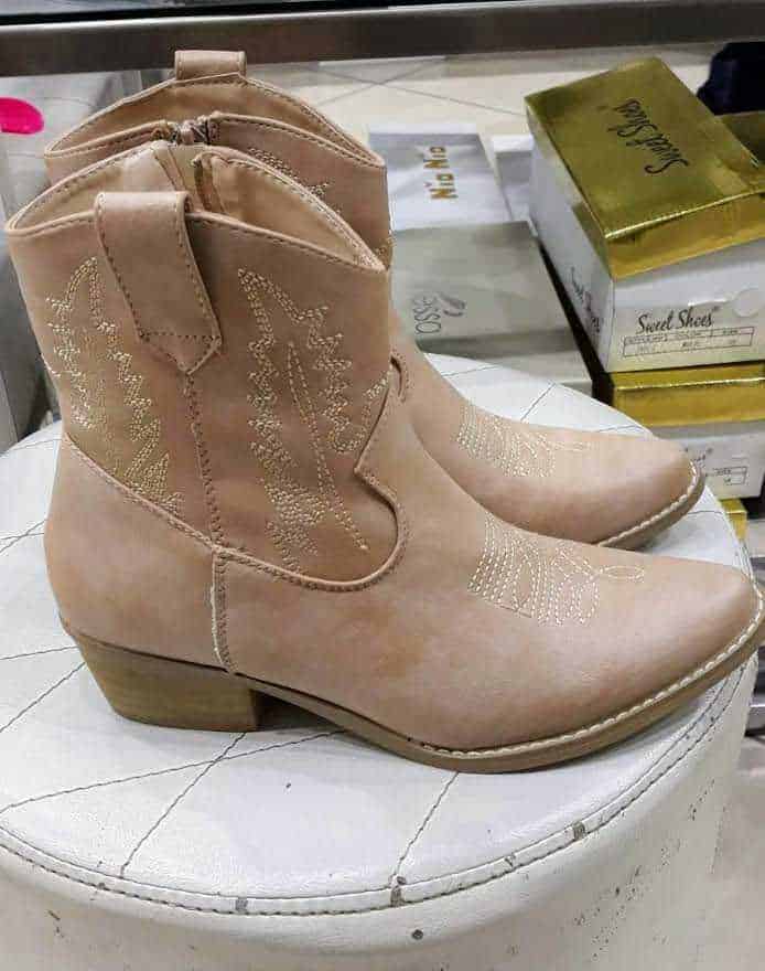 Scarpe donna in pelle beige stivaletti con decorazioni ricamate, stile western, su display di negozio.