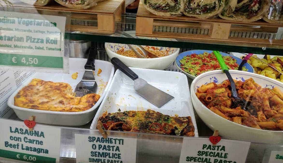 Farcita di verdure e formaggio, rotolo di pita con rucola, aglio e formaggio, di fronte a insalate di pasta fresca, lasagne di carne.