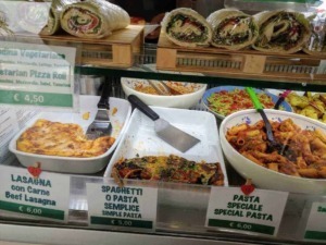 Farcita di verdure e formaggio, rotolo di pita con rucola, aglio e formaggio, di fronte a insalate di pasta fresca, lasagne di carne.