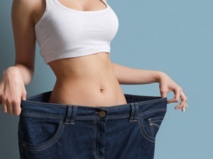 Cattura di una donna che mostra vestiti larghi per evidenziare perdita di peso e dimagrimento, simbolo di successo nel percorso di salute e fitness.