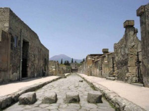Antica strada romana tra macerie e rovine di Pompei, vulcano in lontananza, sito archeologico storico italiano.