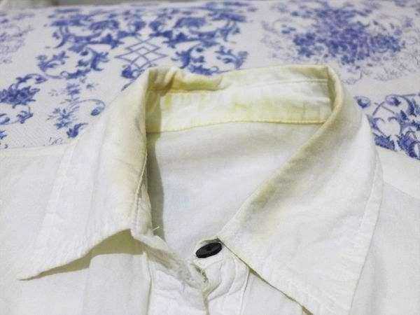 Camicia bianca classica in lino su sfondo di tovaglia blu e bianca con motivi floreali, perfetta per look eleganti e casual, ideale per l'estate e le occasioni formali.