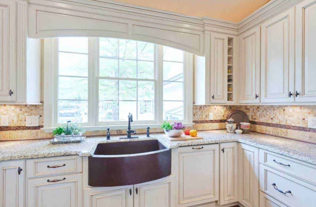Lavandino da cucina in ceramica scura con finestra grande a giorno, mobili eleganti in stile classico e dettagli di marmo, decorazioni fresche con verdure e frutta, ambiente luminoso e accogliente.