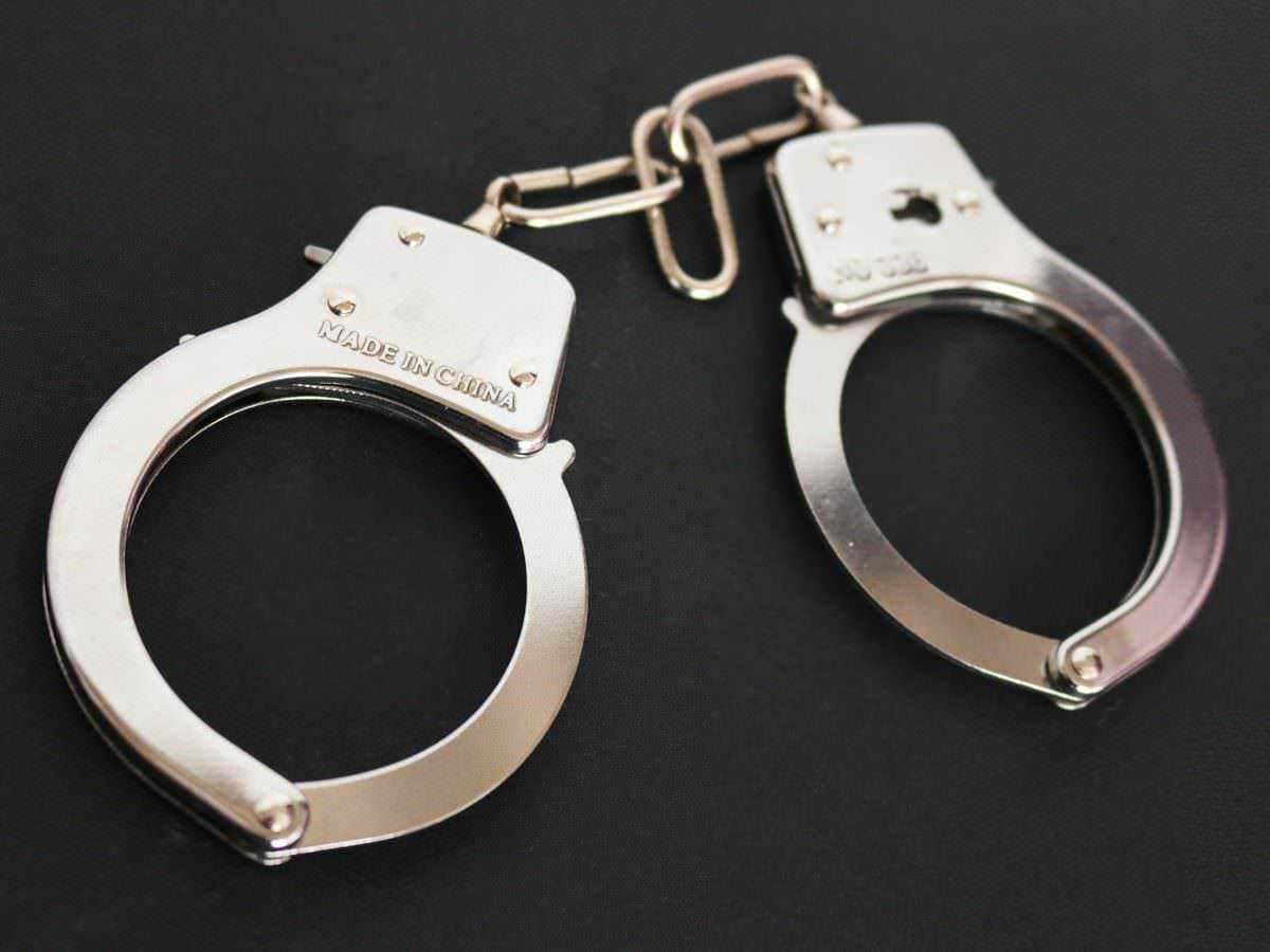 Manette di metallo placcato argento con catenella, simbolo di restrizione e sicurezza, su sfondo nero. Ideale per articoli riguardanti sicurezza, forze dell'ordine, o strumenti di controllo.