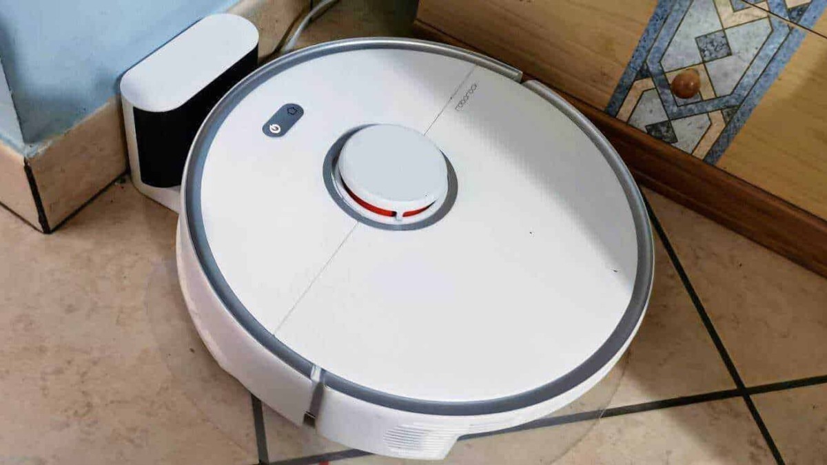 Robot aspirapolvere senza fili in azione su pavimento di ceramica in cucina, con superficie pulita e tecnologia avanzata per la casa intelligente.