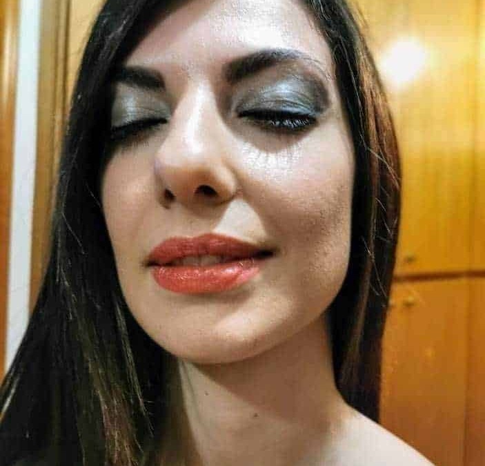 Bellissima donna con trucco elegante e trucco occhi smoky eye, capelli lisci e luminosi, in un ambiente caldo e accogliente.