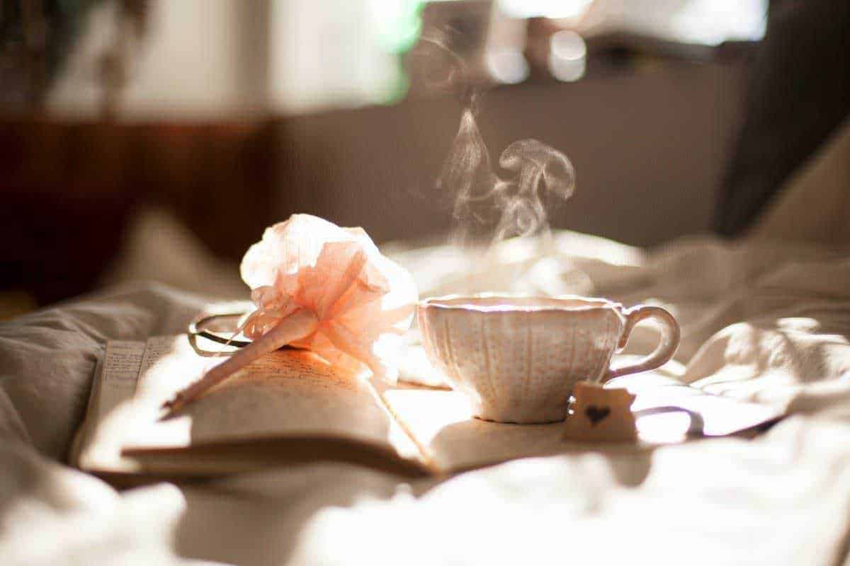 Profumo di tè caldo, fiamma che sprigiona vapore su una tazza da tè e libro aperto, atmosfera tranquilla e rilassante, ideale per la lettura e il relax.