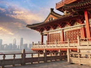Inno cinese tradizionale sul lago di Shanghai al tramonto con skyline moderno in background.