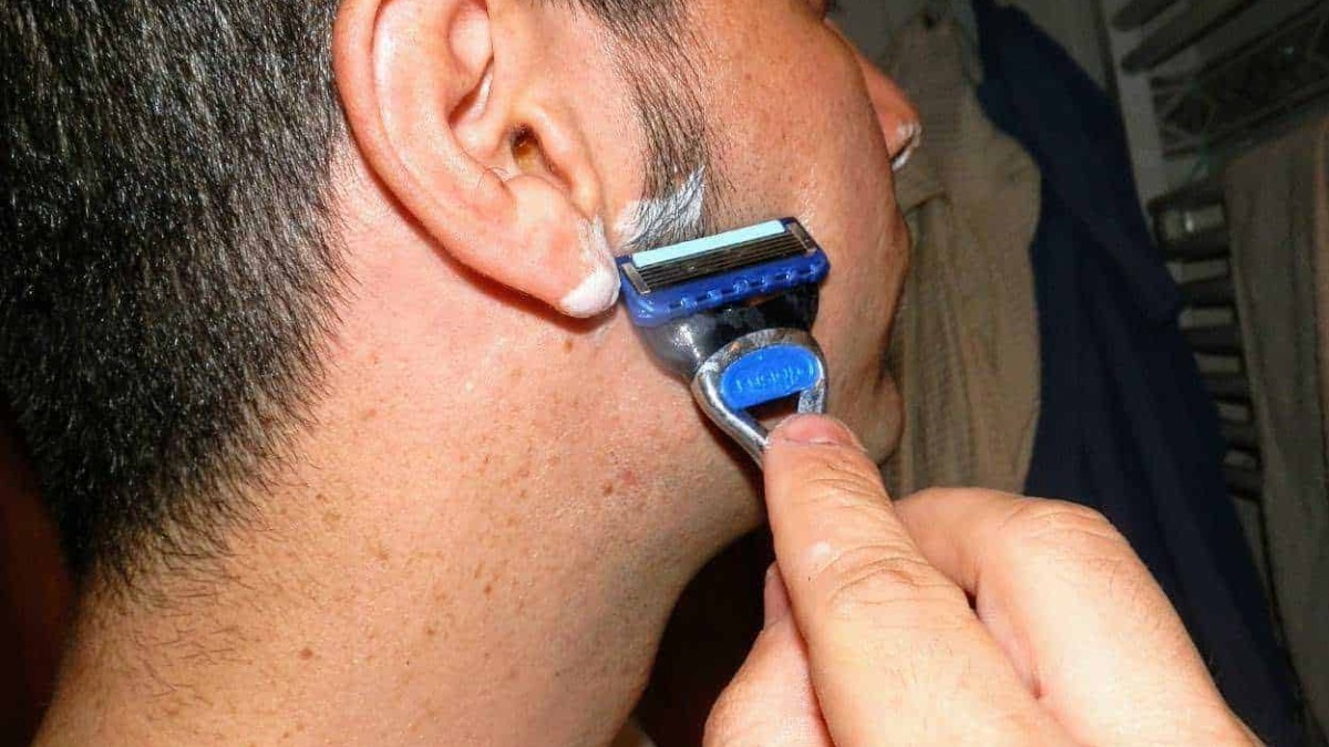 Rf: uomo che si rade con il rasoio elettrico sul viso.