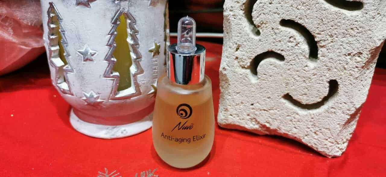 Anti-aging elisir in flacone con contagocce, decorazioni natalizie con albero e luna, ambiente caldo e festoso.