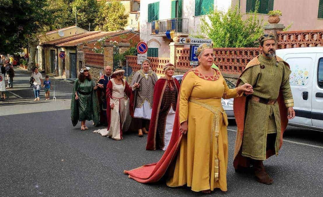 Carovana di persone in costumi medievali che sfilano in strada, atmosfera storica e culturale, evento tradizionale o rievocazione storica in Italia, appunti sul blog.