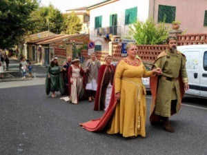 Carovana di persone in costumi medievali che sfilano in strada, atmosfera storica e culturale, evento tradizionale o rievocazione storica in Italia, appunti sul blog.