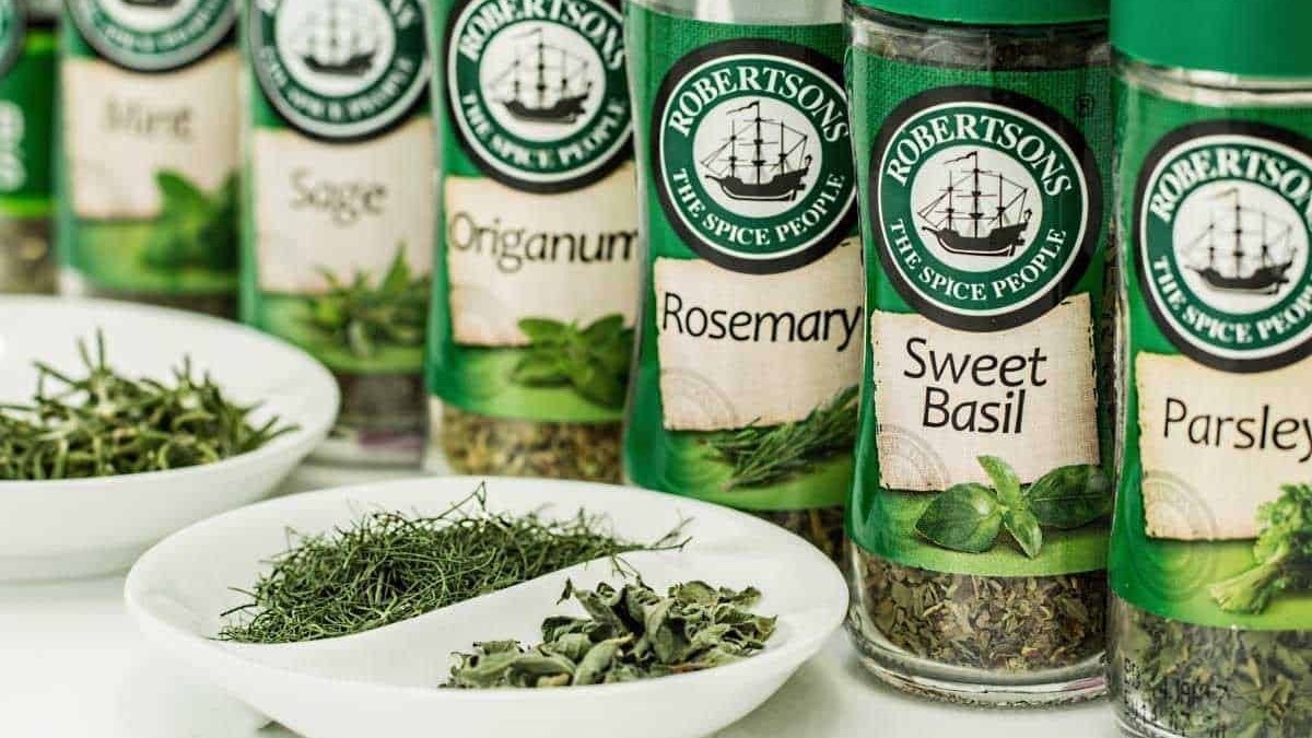 Erbe aromatiche rosa, origano, salvia e timo in barattoli di spezie Robertson's, ideali per cucinare piatti saporiti e profumati. Aromi freschi e secchi per cucina mediterranea e ricette creative.